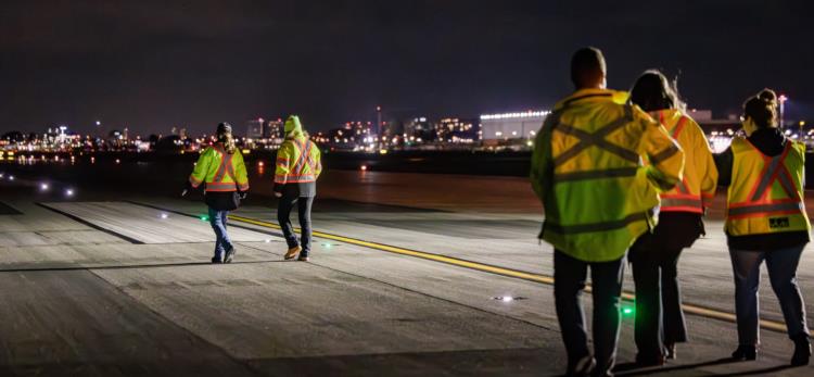 Photo of a group of people walking on the runway of an airfield